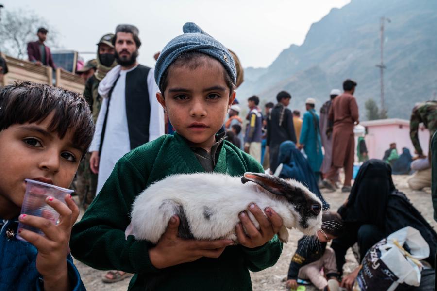 A young boy carrying a rabbit.